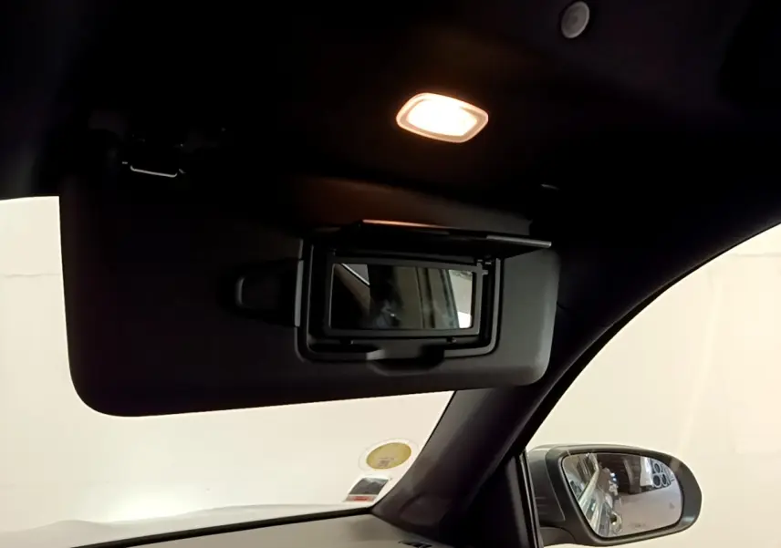 Détail de miroir de courtoisie sur pare-soleil côté conducteur dans l’habitacle sombre d’un Mercedes GLB gris foncé.