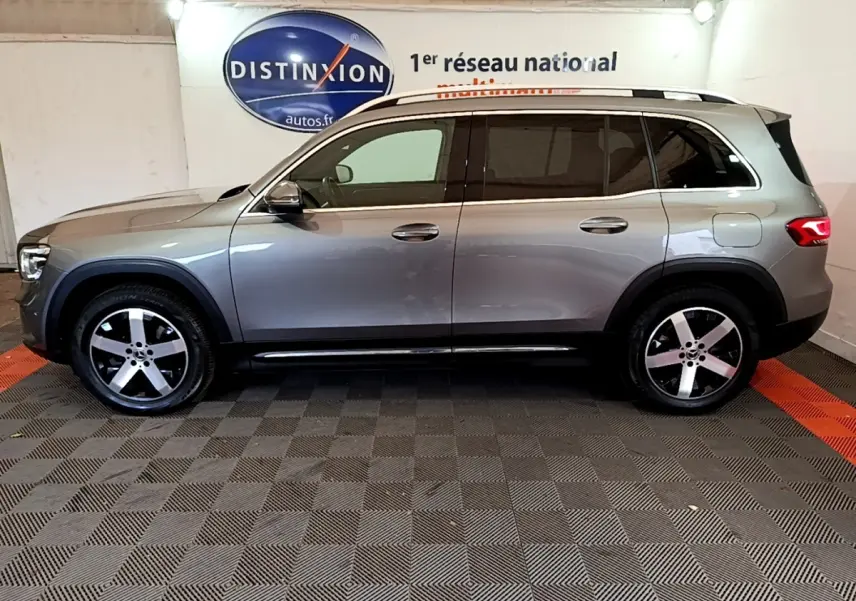 Vue de profil côté gauche d’un Mercedes GLB 200 d Business Line gris foncé en intérieur avec jantes alliage cinq branches.
