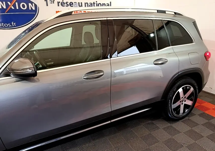 Vue de profil côté gauche du Mercedes GLB 200 d Business Line gris foncé avec jantes alliage et barres de toit chromées.