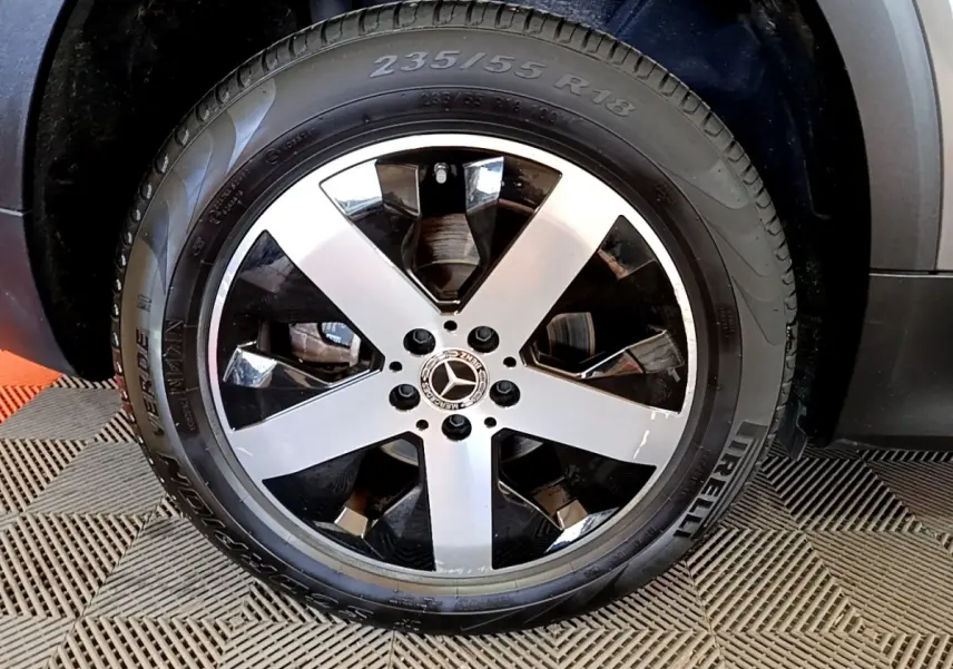 Gros plan sur la roue avant droite d’un Mercedes GLB 200 d gris foncé avec jante alliage à cinq branches bicolores.