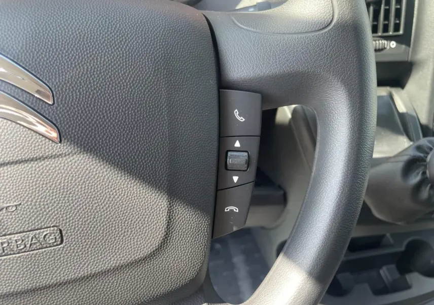 Gros plan sur le volant noir du Citroën Jumper 2023 avec commandes audio intégrées et levier de vitesses manuel visible.