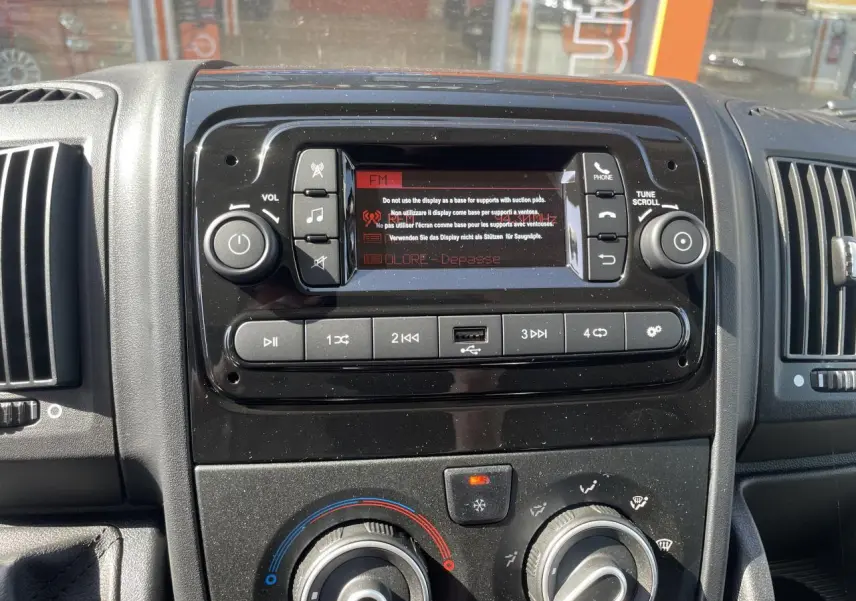 Vue rapprochée du tableau de bord noir du Citroën Jumper 2023, avec système audio et commandes de climatisation.