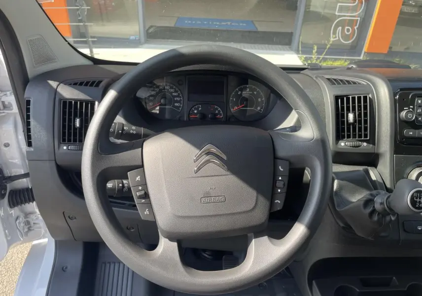 Vue rapprochée du volant et du tableau de bord du Citroën Jumper blanc 2023 avec levier de vitesses manuel et commandes au volant.