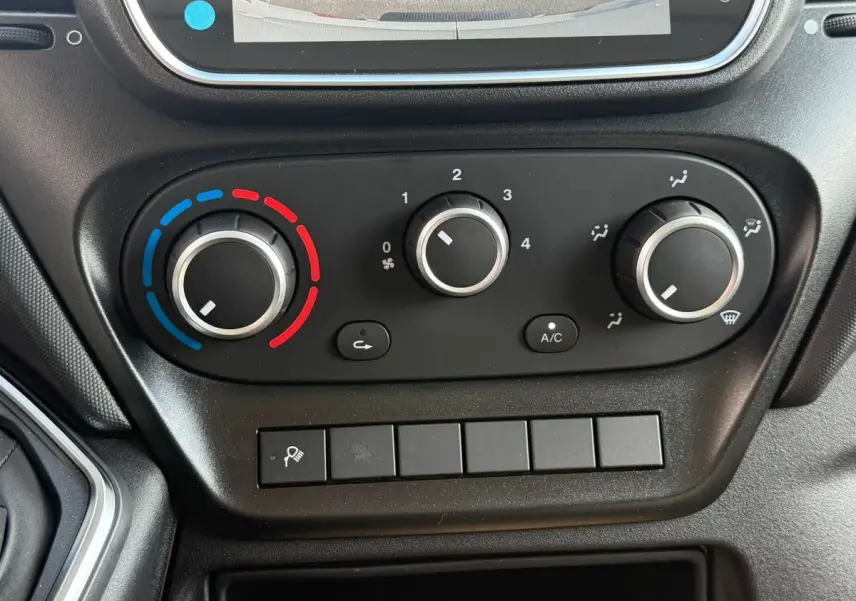 Vue rapprochée des commandes de climatisation du tableau de bord du fourgon Iveco Daily blanc 2026.