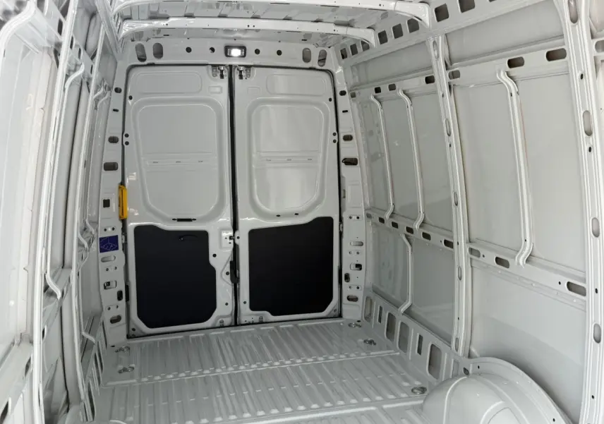 Vue intérieure arrière du fourgon Iveco Daily blanc 2026, montrant l’espace de chargement vide et les portes arrière fermées.