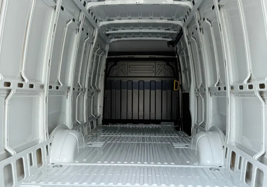 Vue intérieure arrière du fourgon blanc Iveco Daily 35S18 2026, montrant l'espace de chargement vide et la cloison noire.