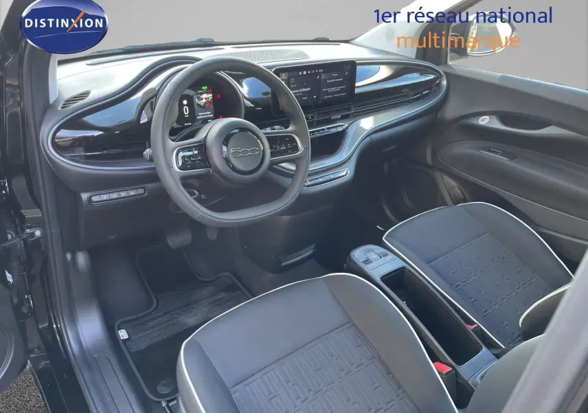 Vue intérieure côté conducteur de la Fiat 500 électrique 2023 noir onyx, avec tableau de bord numérique et sièges tissu noirs.