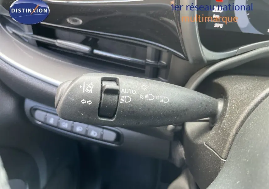 Gros plan sur la commande des feux et clignotants à gauche du volant dans l’habitacle noir d’une Fiat 500 électrique 2023.