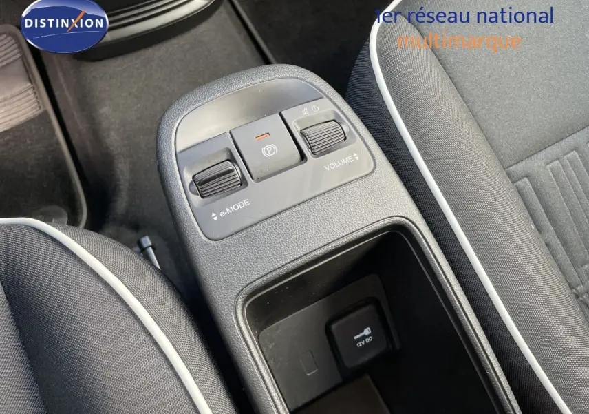 Vue rapprochée de la console centrale de la Fiat 500 électrique noire, avec commandes e-mode et volume visibles.
