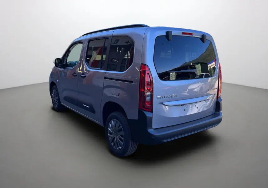 Vue 3/4 arrière gauche du Citroën Berlingo BlueHDi 100 Feel Plus gris Artense avec vitres surteintées et barres de toit.