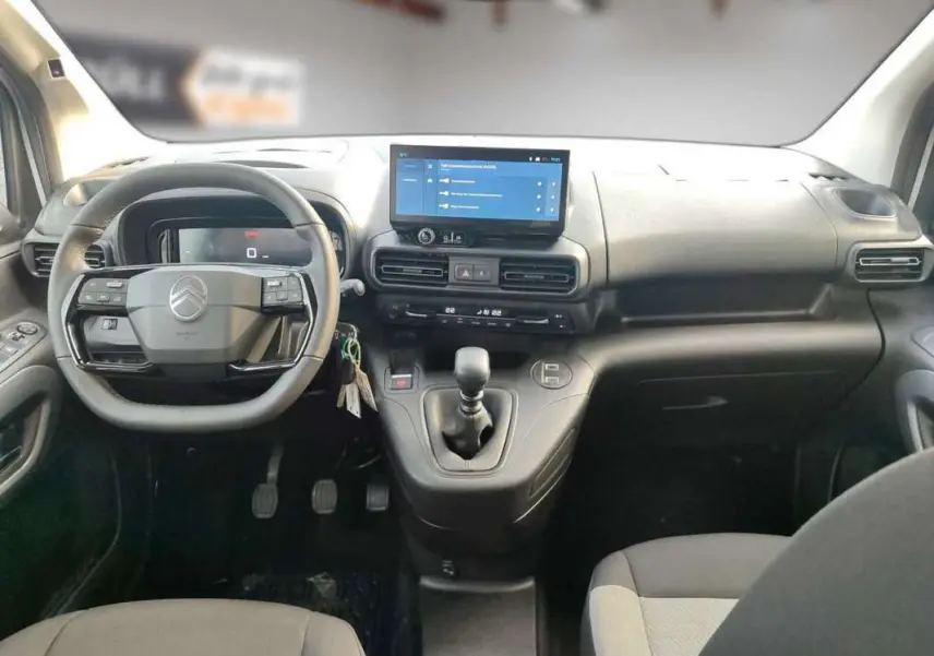 Vue intérieure frontale du tableau de bord du Citroën Berlingo BlueHDi 100 Feel Plus avec volant multifonctions et écran tactile central.