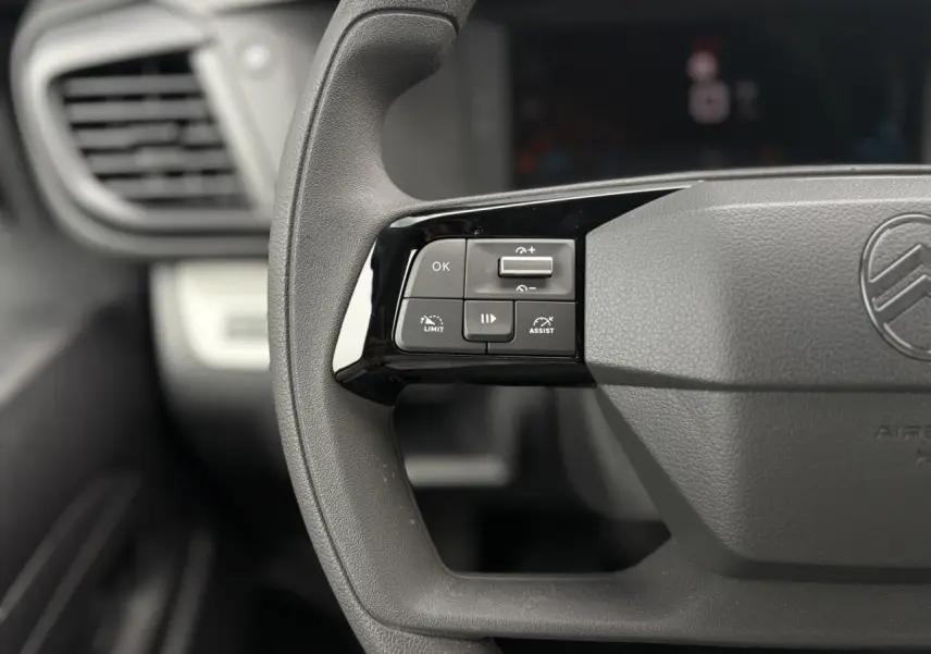 Gros plan sur les commandes au volant noir mat du Citroën Jumpy gris Titane, version 2025, avec logo central visible.