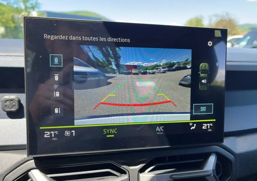 Écran tactile du tableau de bord du Dacia Bigster montrant la caméra multiview arrière avec vue sur parking extérieur.