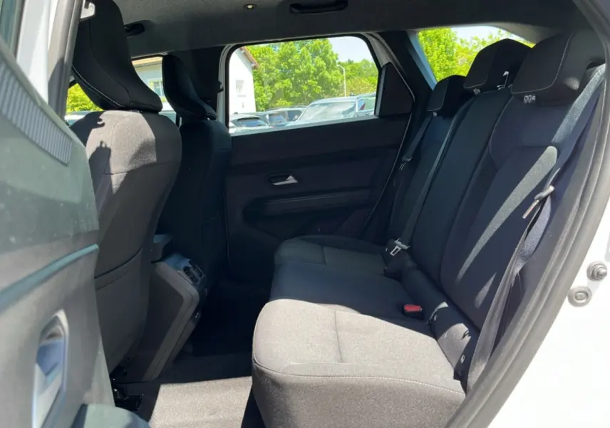 Vue latérale côté droit sur la banquette arrière noire du Dacia Bigster blanc glacier 2025, intérieur spacieux et lumineux.