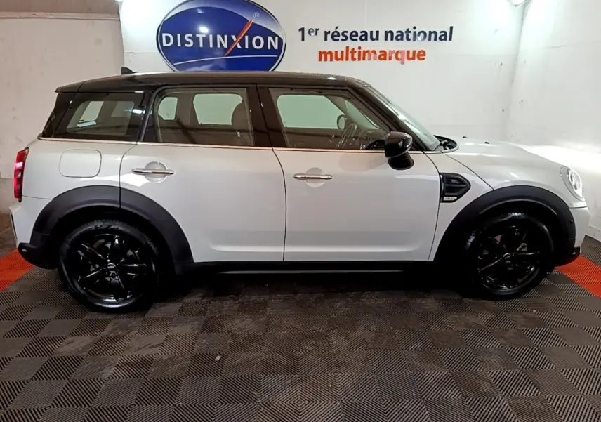 Vue de profil côté gauche d'un MINI Countryman gris clair avec toit noir et jantes noires brillantes.