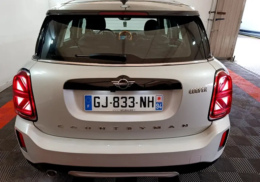 Vue arrière d'une MINI Countryman Cooper gris clair avec feux LED et toit noir dans un garage.