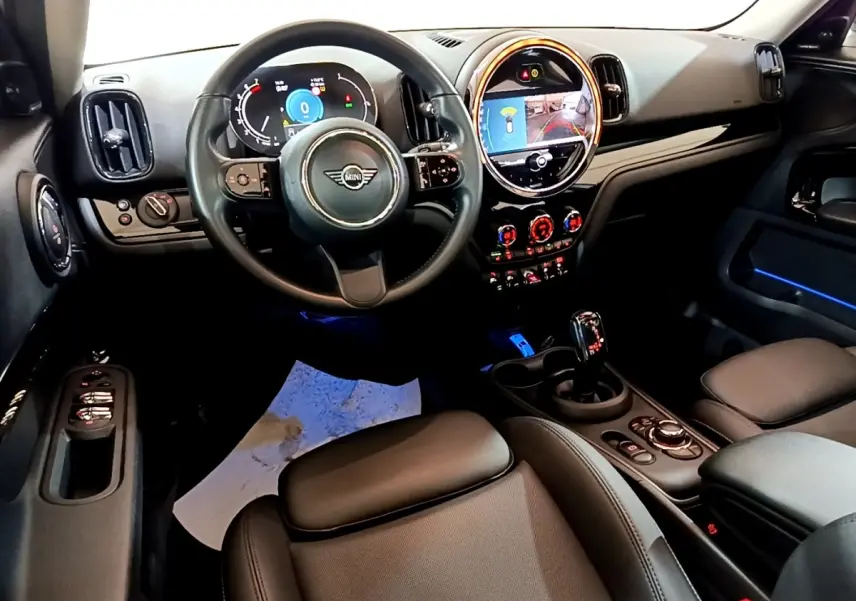 Vue intérieure avant du tableau de bord et volant noir du MINI Countryman Cooper Premium Plus 2022 avec éclairage d'ambiance bleu.