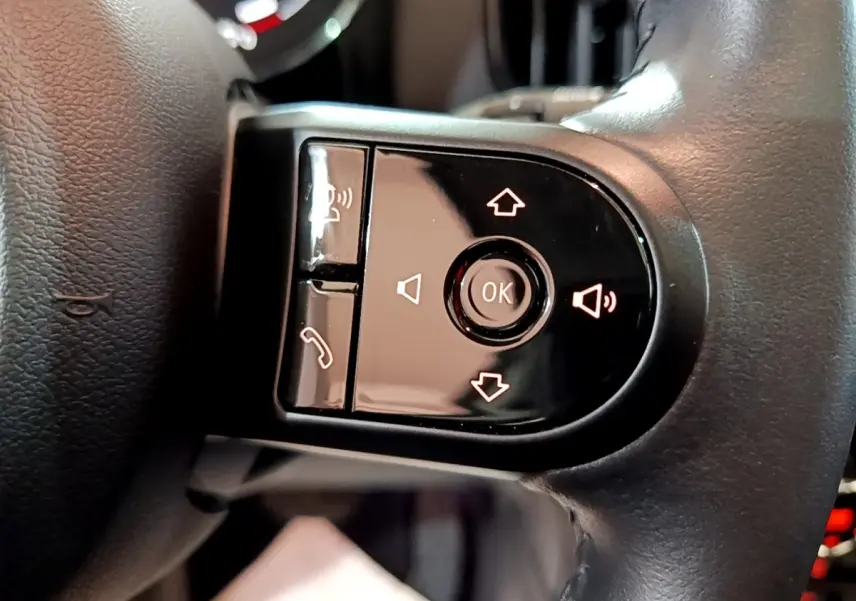 Gros plan sur les commandes noires du volant cuir du MINI Countryman gris clair, avec boutons de volume et appel.