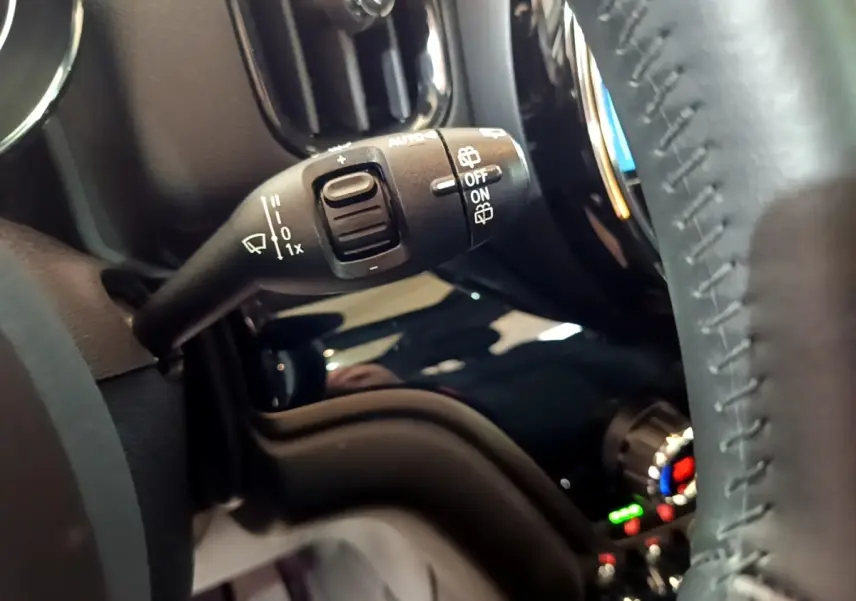 Gros plan sur la commande des essuie-glaces à gauche du volant cuir dans l’habitacle d’une MINI Countryman gris clair.