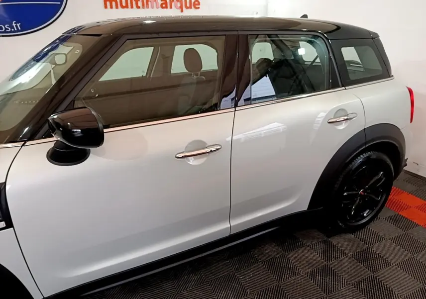Vue latérale droite d'une MINI Countryman gris clair avec toit noir et jantes noires brillantes.