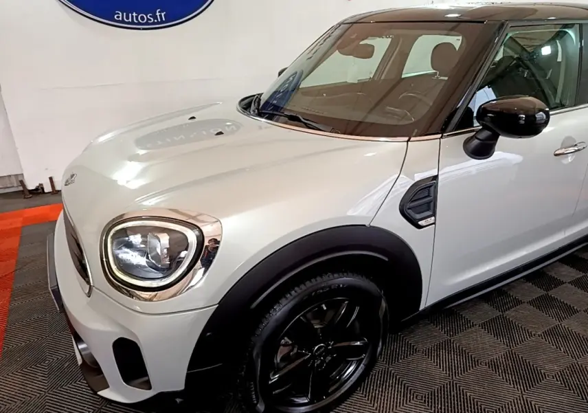 Vue 3/4 avant droit d'une MINI Countryman gris clair avec toit noir et jantes noires brillantes.