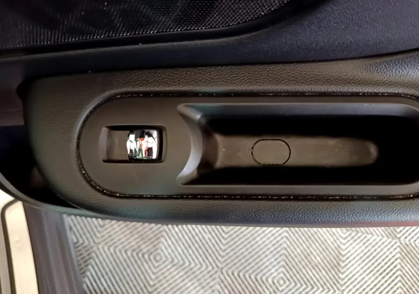 Poignée intérieure de porte noire vue de dessus sur MINI Countryman gris clair, avec bouton de verrouillage intégré.