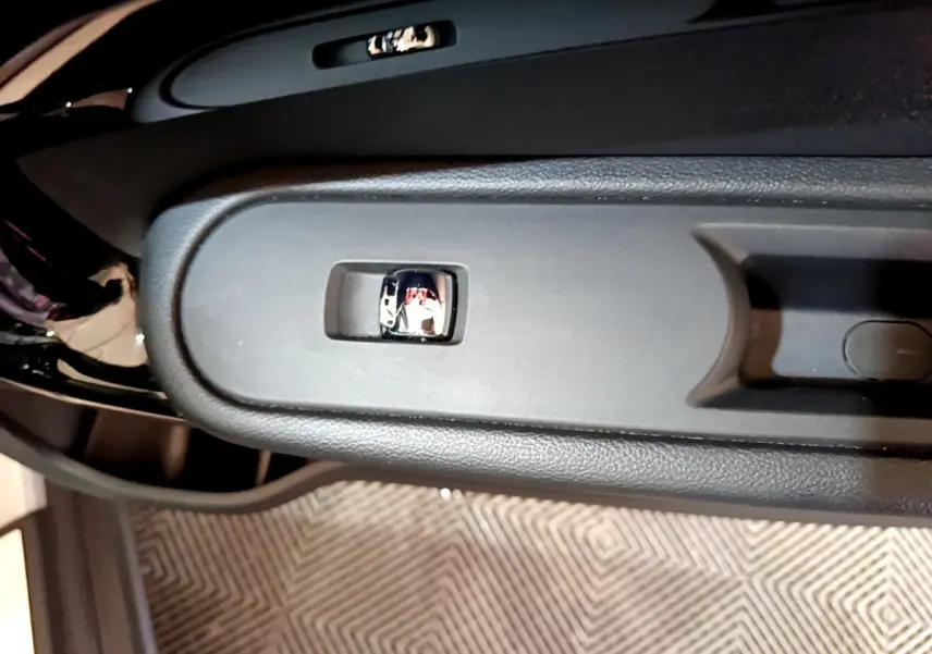 Gros plan sur la commande de lève-vitre côté porte avant d’un MINI Countryman gris clair, intérieur noir.