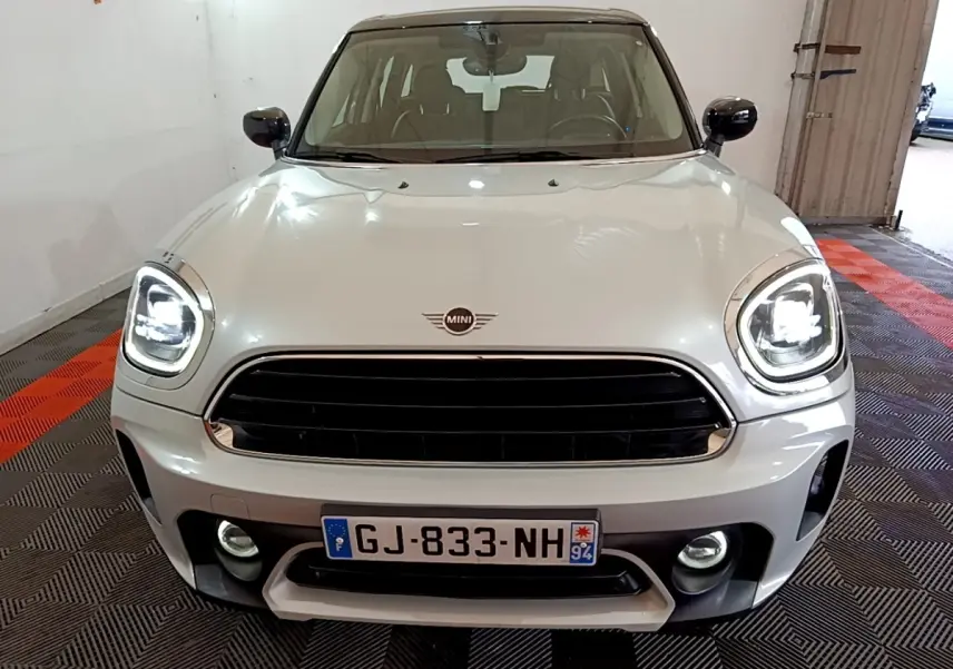 Vue frontale d'une MINI Countryman gris clair avec phares LED allumés et calandre noire brillante.