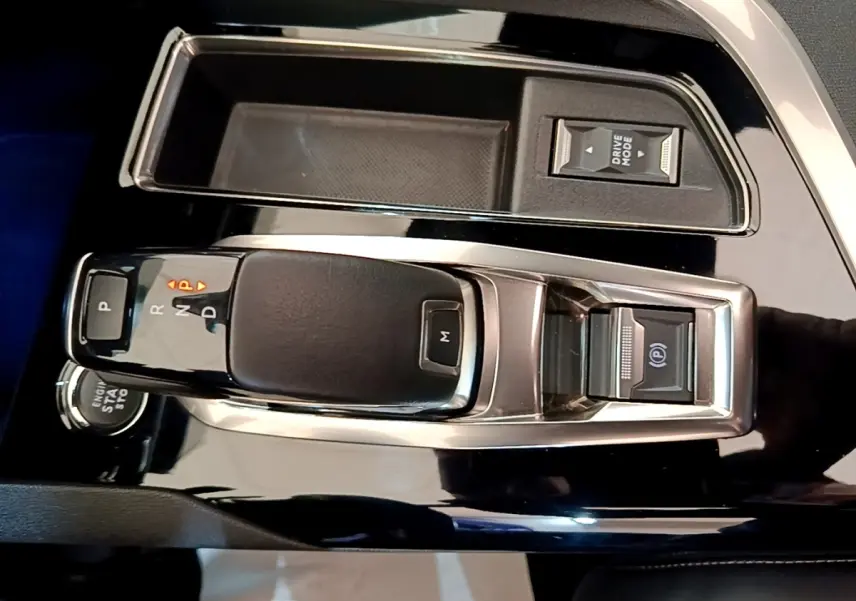 Gros plan sur la console centrale noire brillante du Peugeot 3008 avec levier de vitesses automatique et bouton Drive Mode.