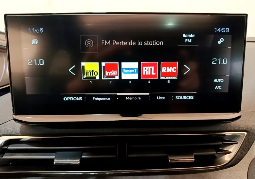 Écran tactile central affichant les stations radio dans l’habitacle d’un Peugeot 3008 noir, vue de face rapprochée.