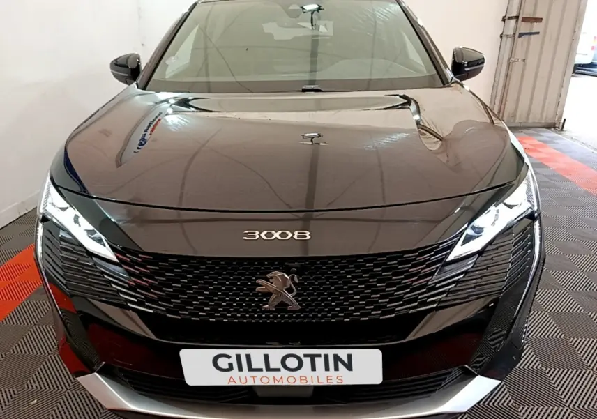 Vue avant d'un Peugeot 3008 noir 2022 avec calandre noire et phares LED allumés dans un garage.