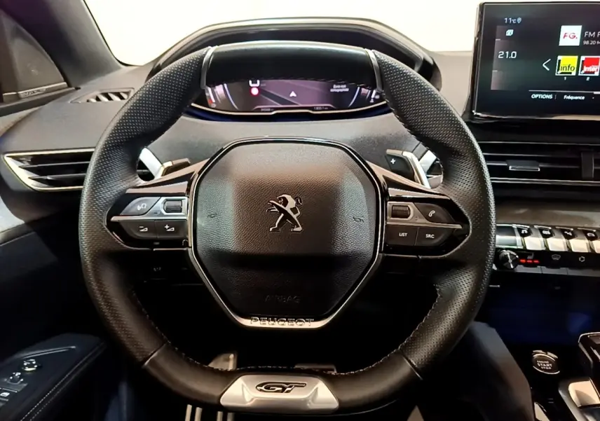 Vue intérieure centrée sur le volant cuir et alu noir du Peugeot 3008 GT Pack 2022 avec tableau de bord digital.