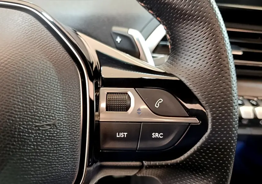 Gros plan sur le volant en cuir perforé noir du Peugeot 3008 GT Pack 2022 avec commandes multifonctions alu.