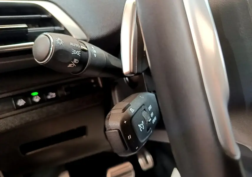 Gros plan sur les commandes au volant en cuir et alu du Peugeot 3008 GT Pack noir, avec boutons multifonctions visibles.