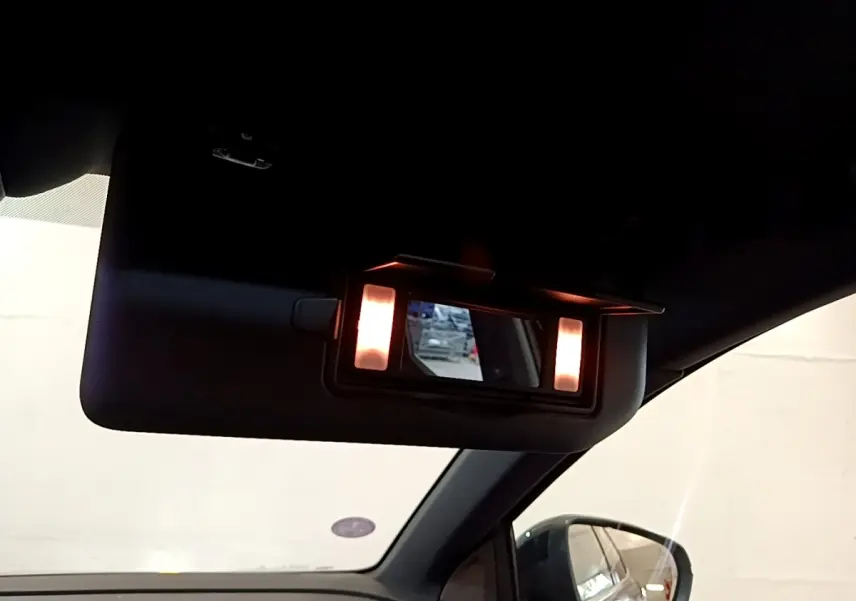 Détail du miroir de courtoisie éclairé sur le pare-soleil côté conducteur d’un Peugeot 3008 noir, intérieur vue latérale.