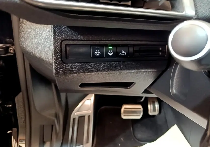 Détail intérieur montrant les commandes d’aide à la conduite et les pédales alu d’un Peugeot 3008 noir, version GT Pack.