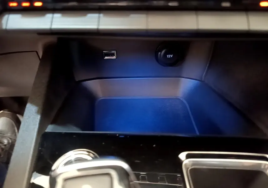 Gros plan sur la console centrale du Peugeot 3008 noir, montrant prise USB, prise 12V et partie inférieure du tableau de bord.