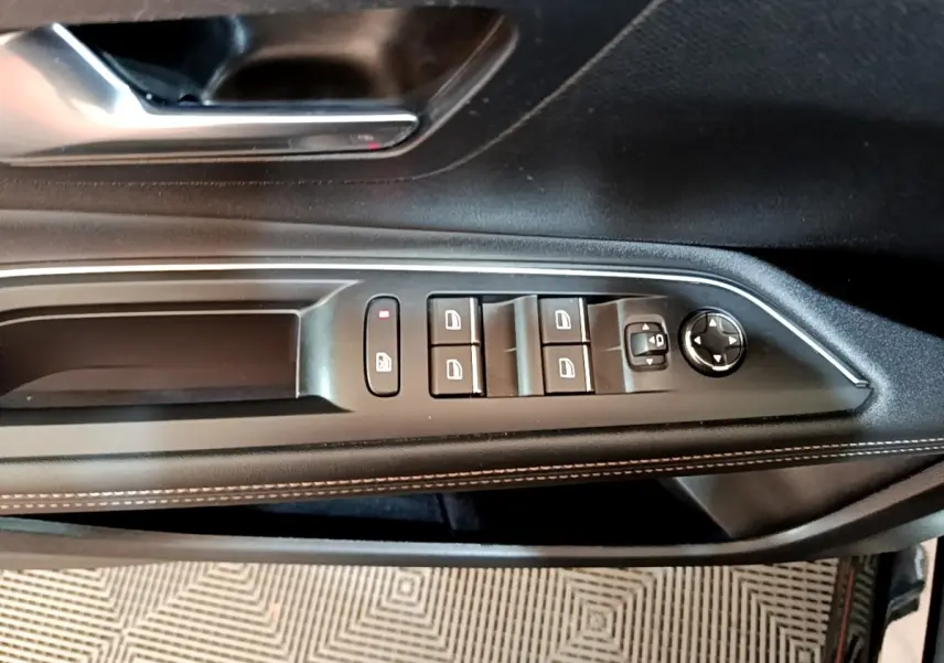 Vue rapprochée du panneau de commandes des vitres côté conducteur d'une Peugeot 3008 noir, avec surpiqûres blanches.