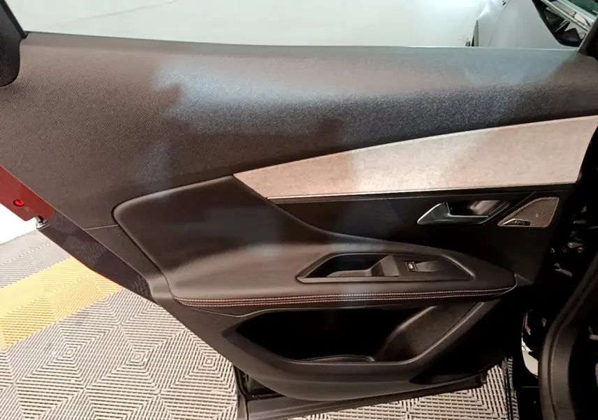 Vue intérieure côté gauche de la porte avant noire du Peugeot 3008 avec habillage cuir et insert tissu clair.