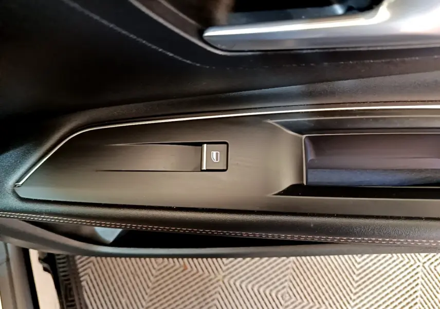 Détail de la commande de lève-vitre sur la porte côté gauche du Peugeot 3008 noir, finition GT Pack 2022.