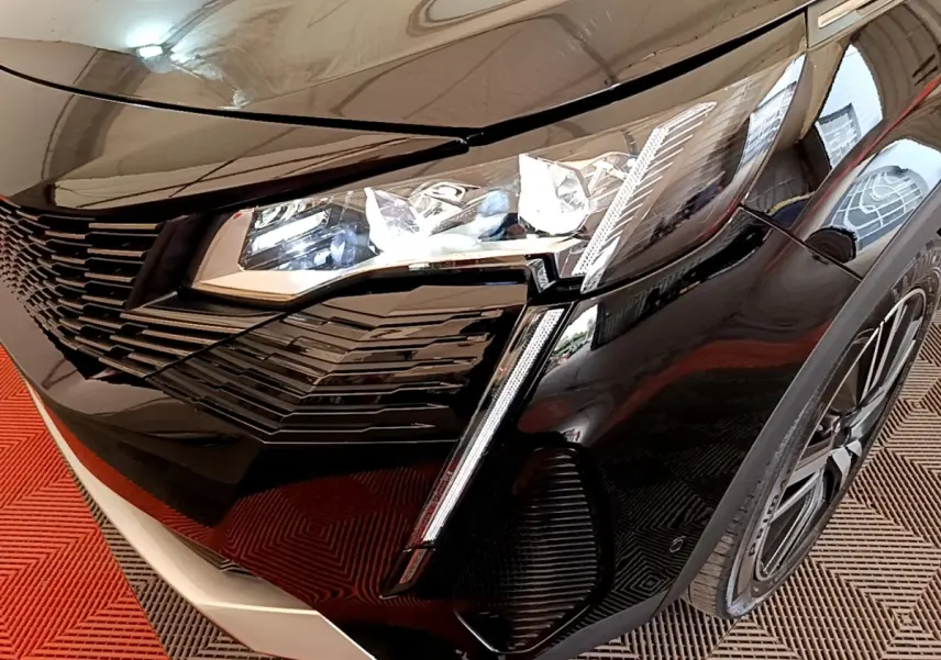 Gros plan sur l'avant droit noir brillant du Peugeot 3008 2022, mettant en valeur le phare LED et la calandre distinctive.