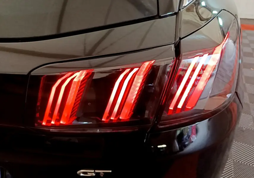 Gros plan sur le feu arrière droit rouge allumé d’un Peugeot 3008 GT Pack noir, avec logo GT visible.