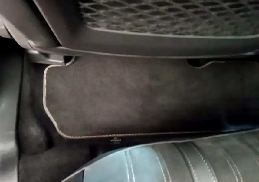 Vue rapprochée du tapis de sol noir et de la partie inférieure d’un siège arrière en cuir dans un Peugeot 3008 noir.