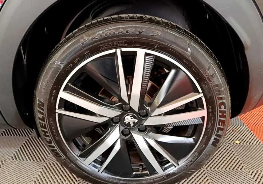 Gros plan sur la roue avant droite noire avec jante alliage bicolore du Peugeot 3008 GT Pack 2022.