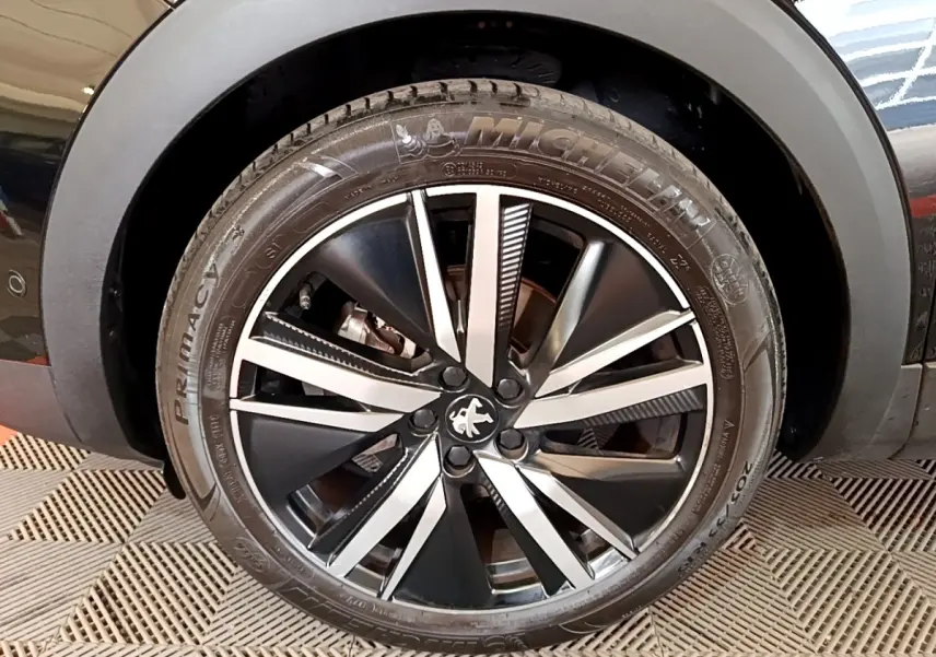 Gros plan sur la jante alliage noire et argentée d’un Peugeot 3008 noir, avec pneu Michelin visible.