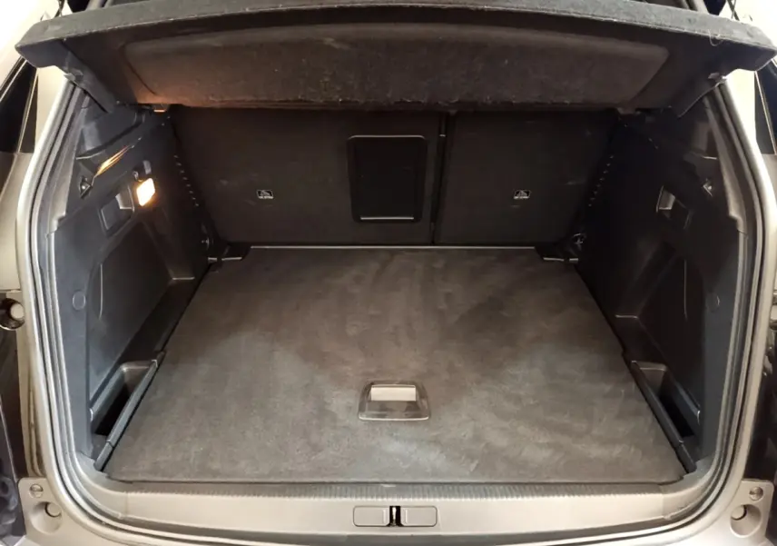 Vue arrière du coffre spacieux et propre du Peugeot 3008 noir, avec éclairage intérieur et revêtement sombre.