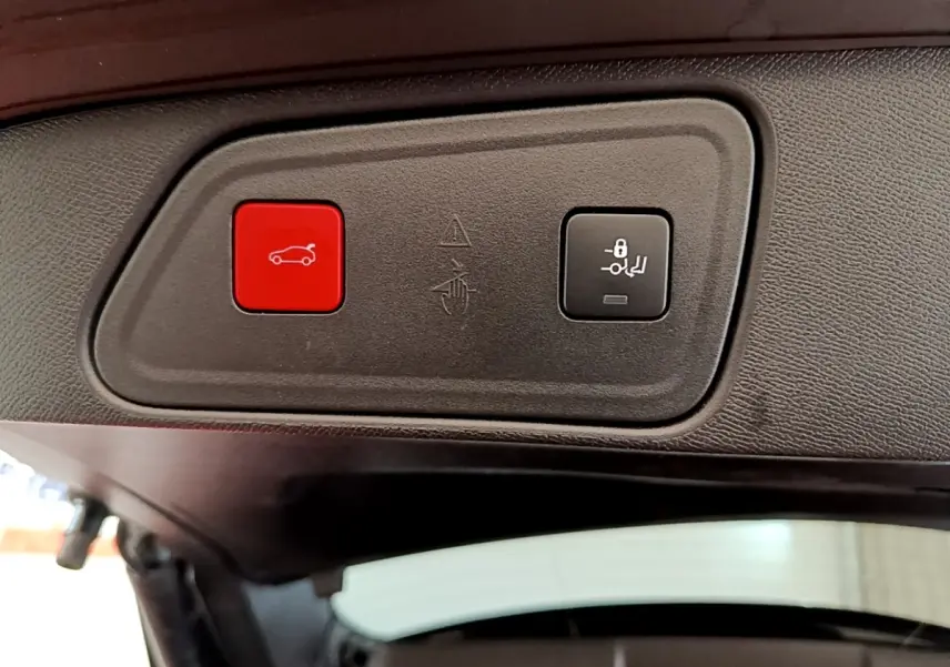 Gros plan sur les boutons d'ouverture et de verrouillage électrique du coffre du Peugeot 3008 noir, vue intérieure arrière.