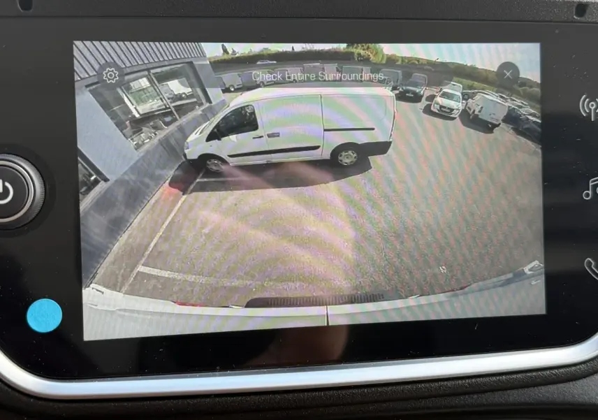 Vue caméra de recul montrant un utilitaire Iveco Daily blanc garé de côté contre un mur dans un parking extérieur.