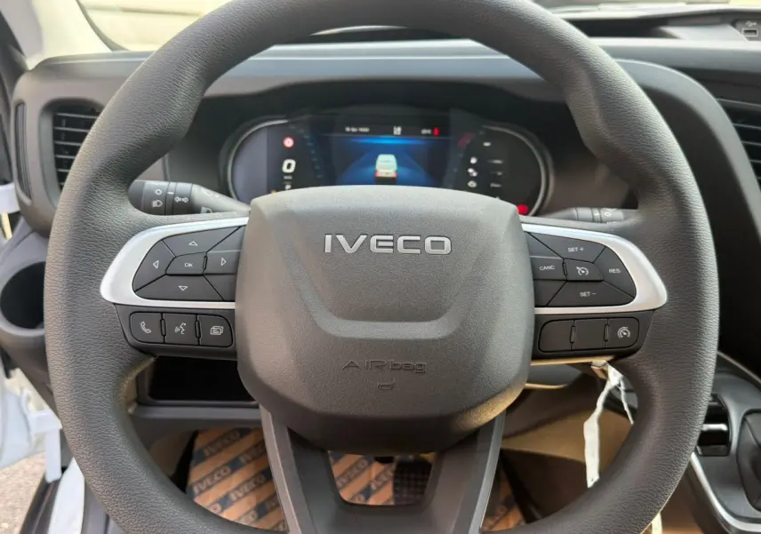 Vue rapprochée du volant noir de l'Iveco Daily 35S18 2026 avec commandes intégrées et tableau de bord numérique.