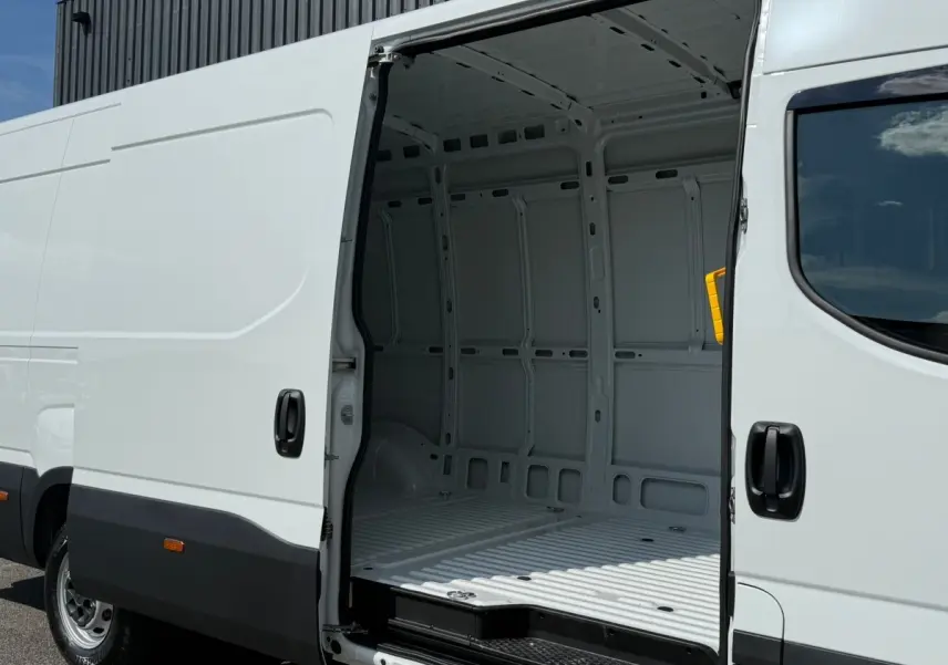IVECO Daily blanc vu de côté droit avec porte latérale ouverte montrant l'intérieur vide du fourgon.